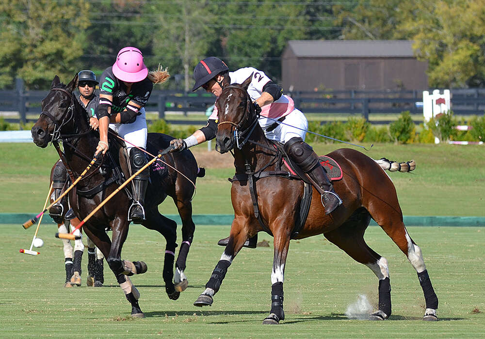 SIG's Malia Bryan goes for the backshot as Out East team owner, John Humphreys, hammers the ball forward.