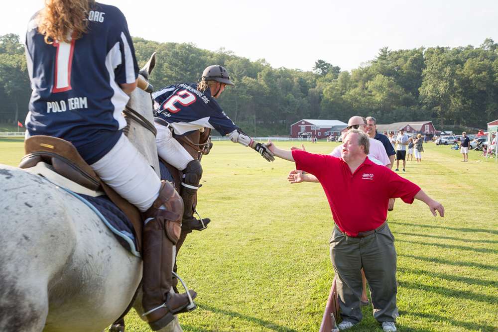Players high-five fans during an exhibition match at Farmington Polo Club.